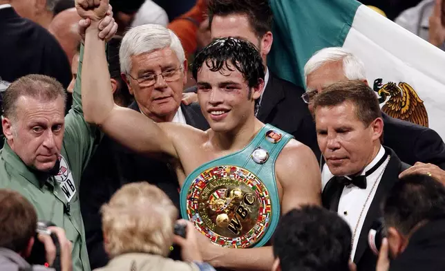 FILE - Julio Cesar Chavez, Jr., center, of Mexico poses with his belt along with his father Julio Cesar Chavez, Sr., right, and referee Jack Reiss after defeating Sebastian Zbik of Germany after their WBC World Middleweight title boxing match, in Los Angeles, June 4, 2011. (AP Photo/Richard Vogel, File)
