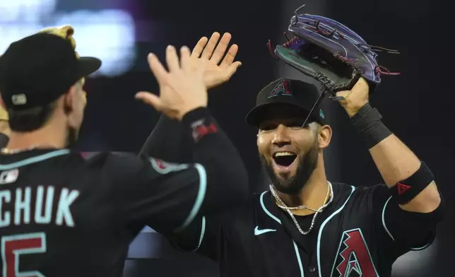 Arizona Diamondbacks' Lourdes Gurriel Jr., right, is congratulated by Randal Grichuk after making a catch on a ball hit by Los Angeles Angels' Jo Adell during the eighth inning of a baseball game Friday, July 11, 2025 in Anaheim, Calif. (AP Photo/Mark J. Terrill)