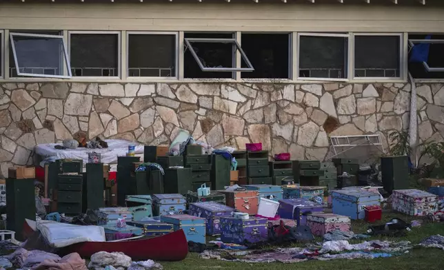 The belongings of campers sit outside one of Camp Mystic's cabins near the Guadalupe River in Hunt, Texas, on Monday, July 7, 2025, after a deadly flash flood swept through the area. (AP Photo/Eli Hartman)