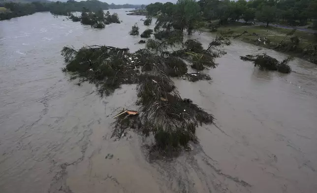 A raging Guadalupe River leaves fallen trees and debris in its wake, Friday, July 4, 2025, in Kerrville, Texas. (AP Photo/Eric Gay)