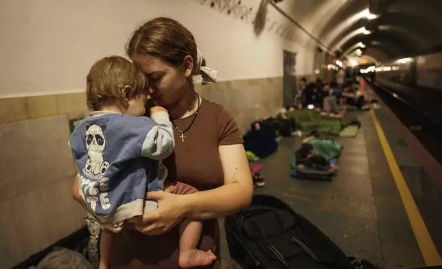 Oleksandra Umanets, 23, calms her 10-month-old son as they take cover on the platform of a metro station during a Russian attack on Kyiv, Ukraine, on Thursday, July 10, 2025. (AP Photo/Evgeniy Maloletka)
