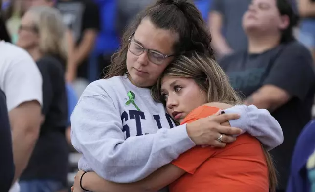 Mourners embrace during a vigil for Guadalupe River flooding victims at Tivy Antler Stadium on Wednesday, July 9, 2025, in Kerrville, Texas. (AP Photo/Ashley Landis)
