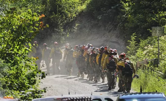 A line of wildland firefighters arrive at the scene the day after a shooter ambushed and killed multiple firefighters responding to a wildfire at Canfield Mountain Monday, June 30, 2025, in Coeur D'Alene, Idaho. (AP Photo/Lindsey Wasson)