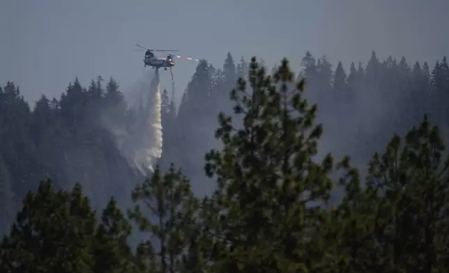 A firefighting aircraft drops water on a wildfire the day after a shooter ambushed and killed multiple firefighters responding to a wildfire at Canfield Mountain Monday, June 30, 2025, in Coeur D'Alene, Idaho. (AP Photo/Lindsey Wasson)