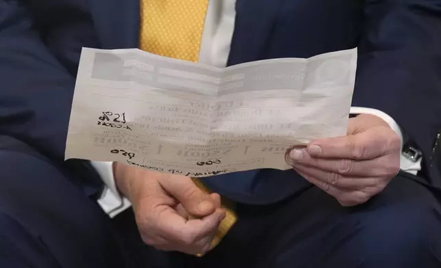 President Donald Trump holds a paper after reaching a trade deal with European Commission President Ursula von der Leyen at the Trump Turnberry golf course in Turnberry, Scotland Sunday, July 27, 2025. (AP Photo/Jacquelyn Martin)