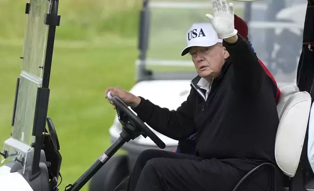 President Donald Trump waves to reporters as he steers his golf cart at the Trump Turnberry golf course in Turnberry, Scotland, Sunday, July 27, 2025.(AP Photo/Alastair Grant)