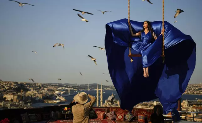 A tourist takes photos in an open-air studio with a view of the Bosphorus in Istanbul, Turkey, Saturday, July 19, 2025. (AP Photo/Emrah Gurel)
