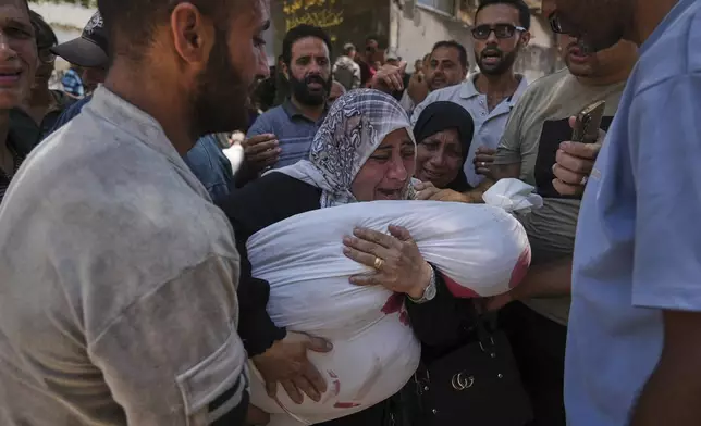Palestinians mourn their relatives who were killed while trying to reach aid trucks entering northern Gaza through the Zikim crossing with Israel, at Shifa Hospital in Gaza City on Sunday, July 20, 2025. (AP Photo/Jehad Alshrafi)