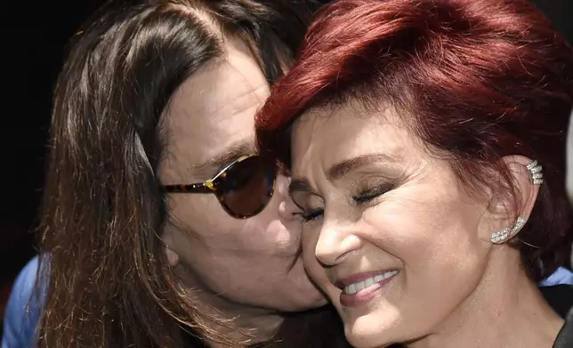 FILE - Ozzy Osbourne kisses his wife Sharon during the "Ozzfest Meets Knotfest" news conference at the Hollywood Palladium, May 12, 2016, in Los Angeles. (Photo by Chris Pizzello/Invision/AP, File)