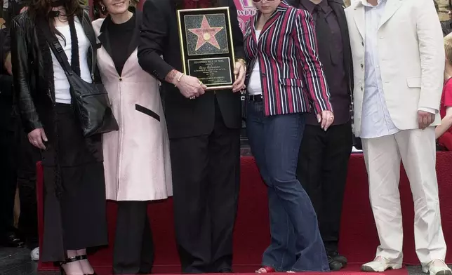 FILE - Metal-rock star Ozzy Osbourne holds a replica of his new star on the Hollywood Walk of Fame as he poses with his family during a ceremony on April 12, 2002, in Los Angeles. Pictured with Osbourne, from left, are Aimee, Sharon, Kelly, Jack and Louis. (AP Photo/Nick Ut, File)