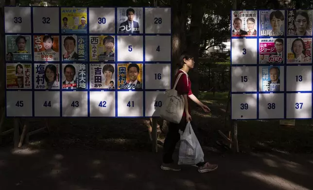 A pedestrian passes an election board displaying posters of candidates for the upcoming July 20 upper house election in Tokyo, Friday, July 18, 2025. (AP Photo/Louise Delmotte)