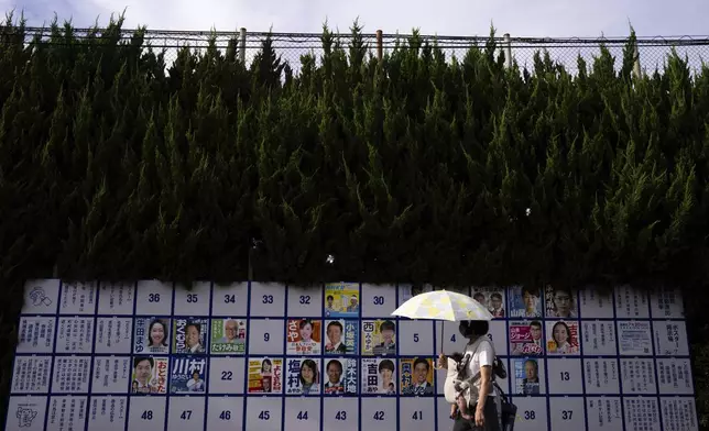A pedestrian passes an election board displaying posters of candidates for the upcoming July 20 upper house election in Tokyo, Friday, July 18, 2025. (AP Photo/Louise Delmotte)