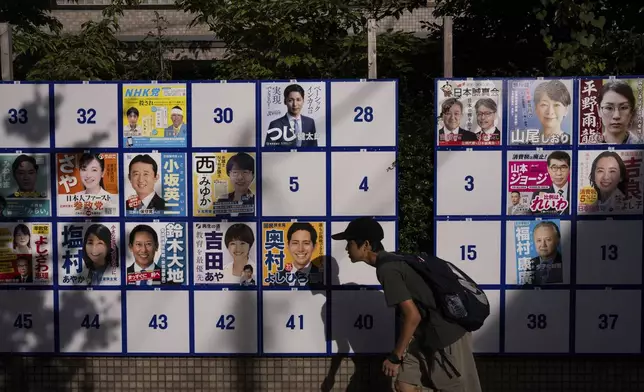 A pedestrian passes an election board displaying posters of candidates for the upcoming July 20 upper house election in Tokyo, Friday, July 18, 2025. (AP Photo/Louise Delmotte)