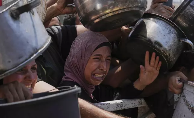 Palestinians struggle to get donated food at a community kitchen, in Gaza City, northern Gaza Strip, Saturday, July 26, 2025. (AP Photo/Abdel Kareem Hana)