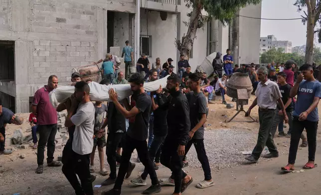 Palestinians carry the body of a person who was killed while trying to reach aid trucks entering northern Gaza through the Zikim crossing with Israel, during his funeral outside Shifa Hospital, in Gaza City, Saturday, July 26, 2025. (AP Photo/Abdel Kareem Hana)