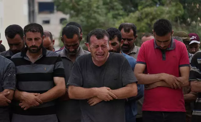 Palestinians pray over the body of a person who was killed while trying to reach aid trucks entering northern Gaza through the Zikim crossing with Israel, at Shifa Hospital, in Gaza City, Saturday, July 26, 2025. (AP Photo/Abdel Kareem Hana)