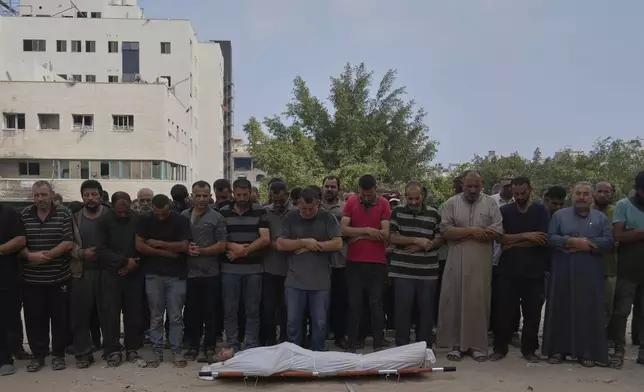 Palestinians pray over the body of a person who was killed while trying to reach aid trucks entering northern Gaza through the Zikim crossing with Israel, at Shifa Hospital, in Gaza City, Saturday, July 26, 2025. (AP Photo/Abdel Kareem Hana)