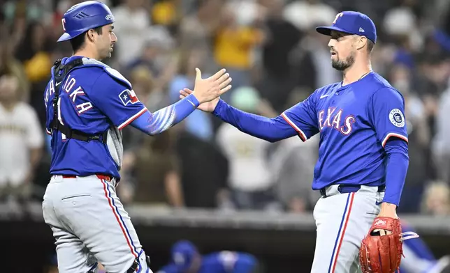 Texas Rangers relief pitcher Robert Garcia (62) and Kyle Higashioka (11) celebrate after the Rangers beat the San Diego Padres in a baseball game Saturday, July 5, 2025. (AP Photo/Denis Poroy)