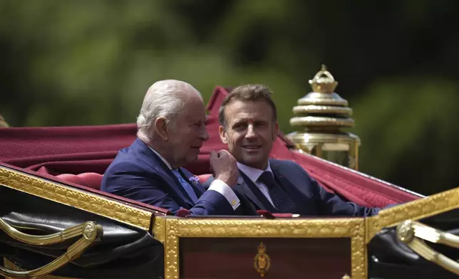 Britain's King Charles III and France's President Emmanuel Macron, right, travel in a 1902 State Landau on a state drive to Windsor Castle in Windsor, England, Tuesday July 8, 2025, on the first day of a three-day state visit to Britain. (Andrew Matthews/Pool via AP)