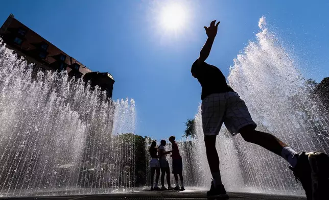Young people walk through the water installation "Hexagonal Water Pavilion" by Danish artist Jeppe Hein in front of the Neues Museum in Nuremberg, Germany, Wednesday, July 2, 2025. (Daniel Karmann/dpa via AP)