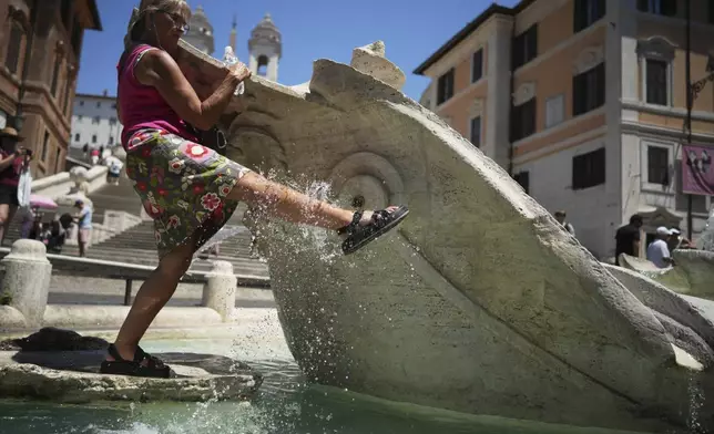 A woman refreshes her legs at Rome's historical Barcaccia fountain, Tuesday, July 1, 2025. (AP Photo/Andrew Medichini)