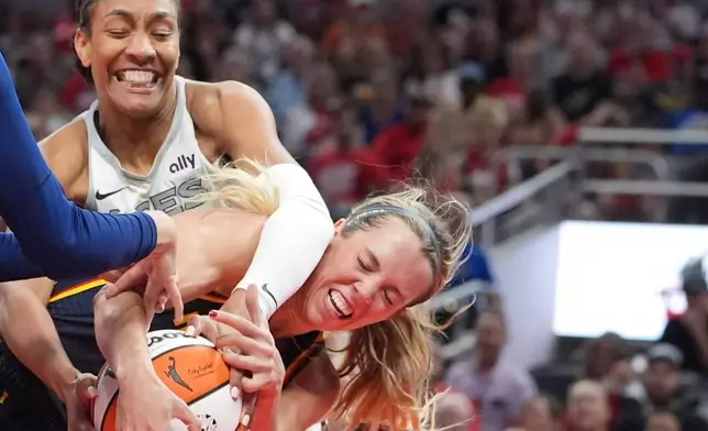 Indiana Fever's Lexie Hull, right, and Las Vegas Aces' A'ja Wilson, left, battle for the ball during the second half of a WNBA basketball game, Thursday, July 3, 2025, in Indianapolis. (AP Photo/Michael Conroy)