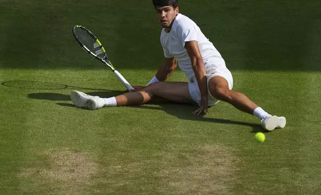 Carlos Alcaraz of Spain slips as he returns a shot by Italy's Jannik Sinner in the men's singles final at the Wimbledon Tennis Championships in London, Sunday, July 13, 2025. (AP Photo/Joanna Chan)