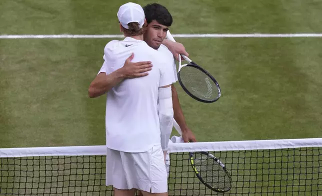Italy's Jannik Sinner, left, greets Carlos Alcaraz of Spain at the net after beating him to win the men's singles final at the Wimbledon Tennis Championships in London, Sunday, July 13, 2025. (AP Photo/Joanna Chan)