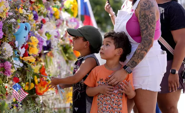 Children visit a memorial wall for flood victims on Friday, July 11, 2025, in Kerrville, Texas. (AP Photo/Gerald Herbert)