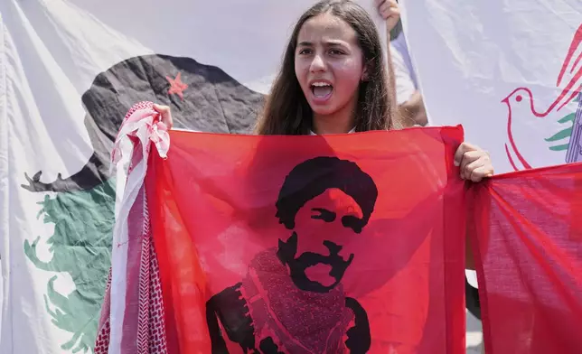 A supporter of Lebanese pro-Palestinian militant George Abdallah, pictured on the flag, who was serving a life sentence for complicity in the 1982 murders of an American and an Israeli diplomat in Paris, shouts slogans as she waits for his arrival at Rafik Hariri International Airport in Beirut, Lebanon, Friday, July 25, 2025. (AP Photo/Hussein Malla)