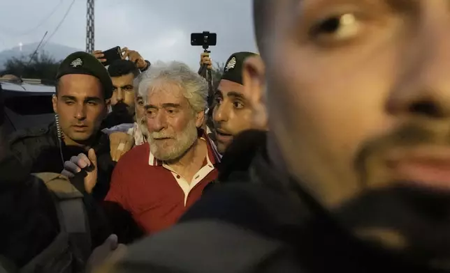 Lebanese pro-Palestinian militant Georges Abdallah, right, who was serving a life sentence for complicity in the 1982 murders of an American and an Israeli diplomat in Paris, is greeted by supporters and surrounded by security forces upon his arrival in Qobayat village, in northern Akkar province, Lebanon, Friday, July 25, 2025. (AP Photo/Hassan Ammar)