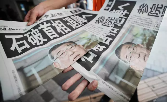 A staff member distributes an extra edition of the Yomiuri Shimbun newspaper, with headline reading "Prime Minister Ishiba towards resignation," Wednesday, July 23, 2025, in Tokyo. (AP Photo/Eugene Hoshiko)