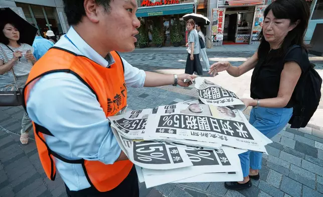 A staff member distributes an extra edition of the Yomiuri Shimbun newspaper reporting that President Donald Trump announced a trade framework with Japan on Tuesday, Wednesday, July 23, 2025, in Tokyo. (AP Photo/Eugene Hoshiko)