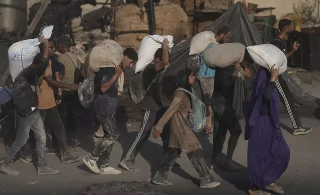 Palestinians carry sacks of flour unloaded from a humanitarian aid convoy that reached Gaza City from the northern Gaza Strip, Saturday, July 26, 2025. (AP Photo/Jehad Alshrafi)