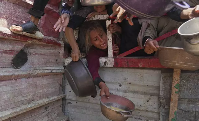 Palestinians struggle to get donated food at a community kitchen, in Gaza City, northern Gaza Strip, Saturday, July 26, 2025. (AP Photo/Abdel Kareem Hana)