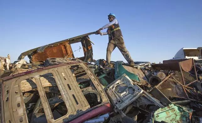 A man rearranges scrap metal at a collection site in Harare, Zimbabwe, Sunday, June 8, 2025. (AP Photo/Aaron Ufumeli)
