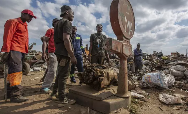 Scrap metal collectors weigh a piece at a site in Harare, Zimbabwe, Sunday, June 8, 2025. (AP Photo/Aaron Ufumeli)