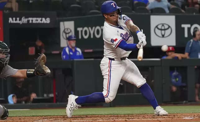 Texas Rangers' Cody Freeman, right, hits a double, that scored teammate Josh Smith, in front of Athletics catcher Shea Langeliers, left, during the fifth inning of a baseball game, Monday, July 21, 2025, in Arlington, Texas. (AP Photo/LM Otero)
