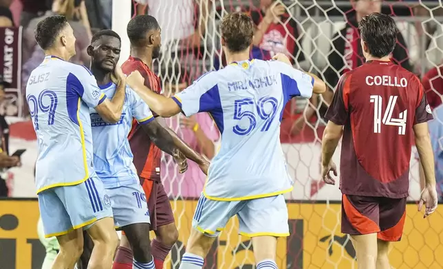 Atlanta United's Emmanuel Latte Lath, second from left, is congratulated Bartosz Slisz (99) and Aleksey Miranchuk (59) after converting the tying penalty kick as Toronto FC's Alonso Coello (14) looks on during second-half MLS soccer match action in Toronto, Saturday, July 12, 2025. (Chris Young/The Canadian Press via AP)