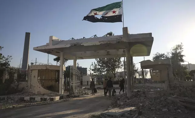 Security members carry belongings as they leave the damaged Syrian Defense Ministry building allegedly hit by several Israeli airstrikes, in Damascus, Syria, Wednesday, July 16, 2025. (AP Photo/Ghaith Alsayed)