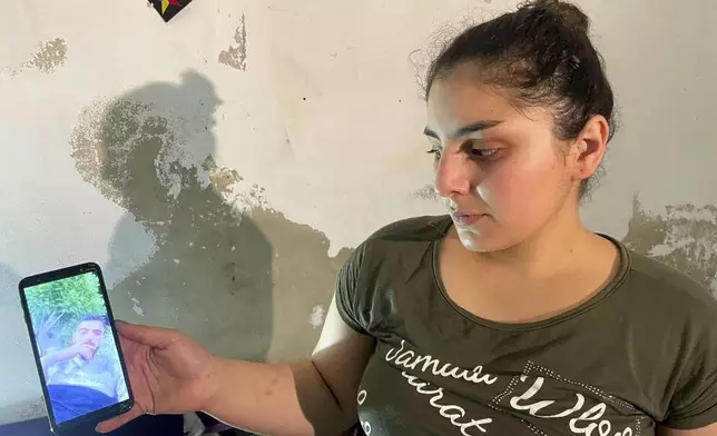 Druze woman, Evelyn Azzam, 20, shows a picture of her husband who was wounded in clashes between Syrian government forces and Druze militias in Sweida, during an interview with The Associated Press in the southern Damascus suburb of Jaramana, Wednesday, July 16, 2025. (AP Photo/Abdulrahman Shaheen)