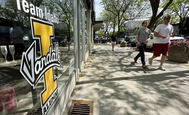 People walk on Main Street in downtown Moscow, Idaho, by a storefront with University of Idaho logo on a window on Tuesday, July 1, 2025. (AP Photos/Manuel Valdes)