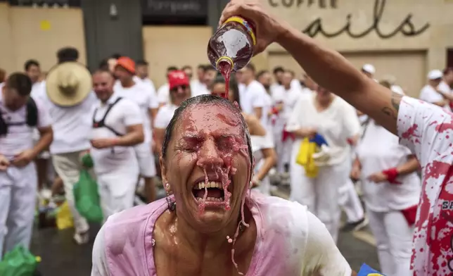 A reveller celebrates early as she waits for the launch of the 'Chupinazo' rocket, marking the official opening of the 2025 San Fermín festival, a nine-day stretch of non-stop partying during Pamplona's famed running of the bulls, in Pamplona, Spain, Sunday, July 6, 2025. (AP Photo/Miguel Oses)