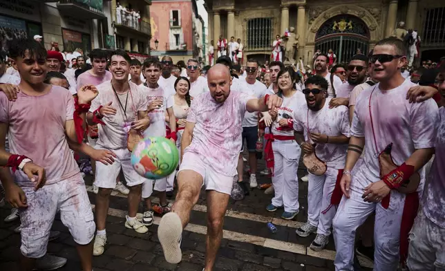 A reveler plays with a ball during the start of nine days of uninterrupted partying in Pamplona's famed running-of-the-bulls festival in Pamplona, Spain, Sunday, July 6, 2025. (AP Photo/Miguel Oses)
