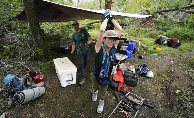 Japanese volunteer Shin Hasegawa, right, helps to set up a kitchen tent as Jake Stowe, program support specialist for Appalachian Trail Conservancy, looks on, during a trail rebuilding project, July 22, 2025, in Unicoi, Tenn. (AP Photo/Erik Verduzco)