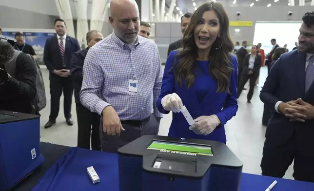U.S. Homeland Security Secretary Kristi Noem holds a test strip before scanning it for traces of explosive material as she attends a security demonstration related to TSA screening and a Biometric Identification Transnational Migration Alert Program (BITMAP) at Arturo Merino Benitez International Airport before departing Santiago, Chile, Wednesday, July 30, 2025. (AP Photo/Alex Brandon, Pool)