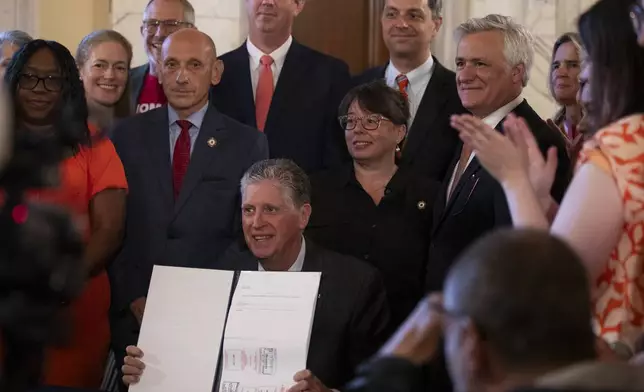 Rhode Island Gov. Dan McKee presents a signed bill that bans the sale of assault-style weapons in the state of Rhode Island at the Rhode Island Statehouse in Providence, Thursday, June 26, 2025. (AP Photo/Sydney Roth)