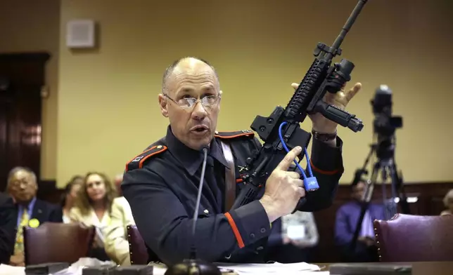 FILE - Rhode Island state police Capt. James Manni gives a demonstration using an AR-15 semi-automatic assault weapon while testifying before a R.I. House Judiciary Committee at The Statehouse, in Providence, R.I., May 1, 2013. (AP Photo/Steven Senne, File)