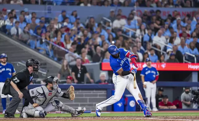 Toronto Blue Jays' Vladimir Guerrero Jr., right, hits a two-run single against the New York Yankees during sixth-inning baseball game action in Toronto, Monday, June 30, 2025. (Thomas Skrlj/The Canadian Press via AP)