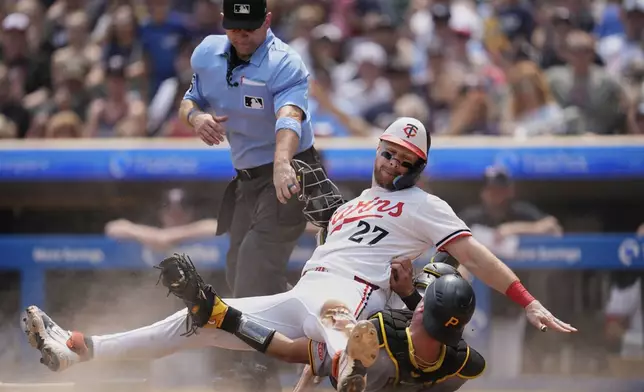 Minnesota Twins' Ryan Jeffers (27) and Pittsburgh Pirates catcher Joey Bart (14) collide after Jeffers was tagged out at home during the second inning of a baseball game Saturday, July 12, 2025, in Minneapolis. (AP Photo/Abbie Parr)